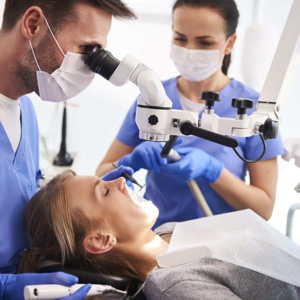 Male dentist working with dental microscope